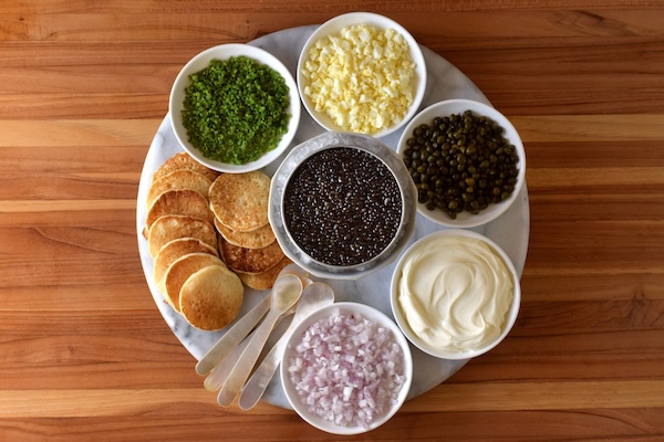 Picture of traditional caviar pairings: chives, egg, crème fraiche, shallot, and capers.